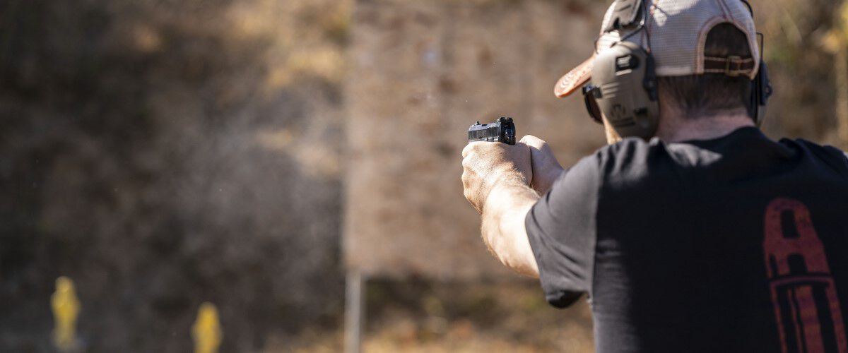 Man shooting a pistol at a couple targets outdoors