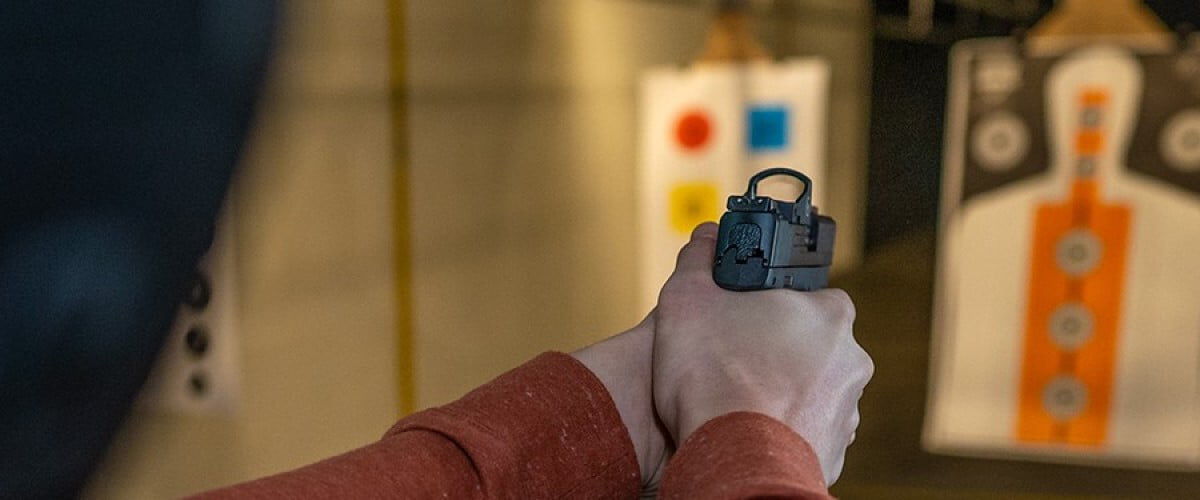 shooter aiming pistol at a target at an indoor range