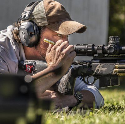 Jim Gilliland looking through a rifle scope while in a prone positionn