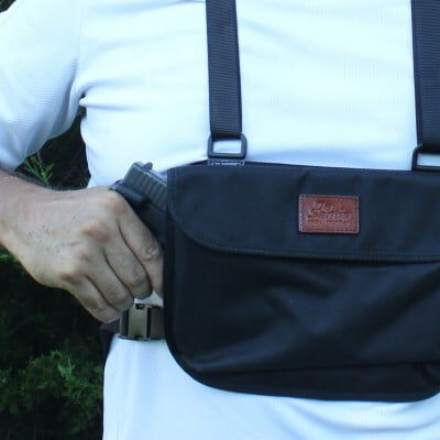 person removing a handgun from a bag on their chest