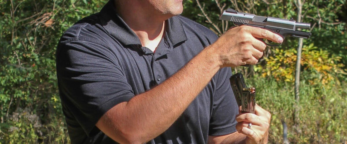 shooter holding two magazines and a handgun