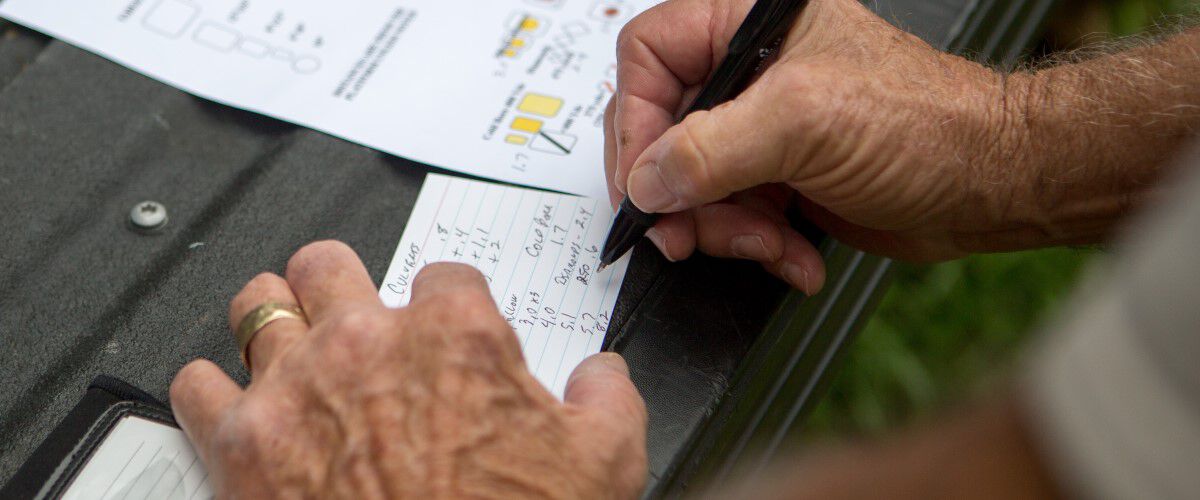 man writing down data on a notecard