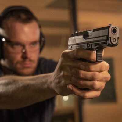 Man holding pistol with both hands at in indoor range