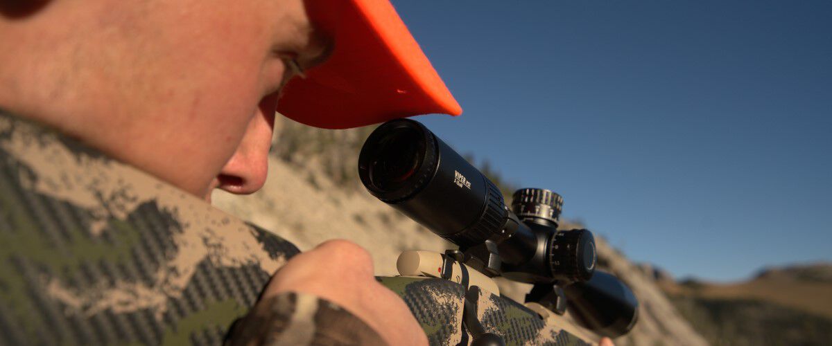 hunter looking down a rifle scope outside