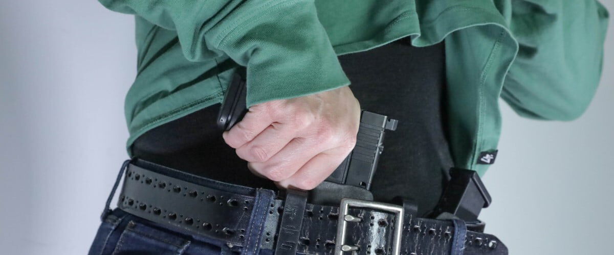 person pulling a handgun from front of their pants