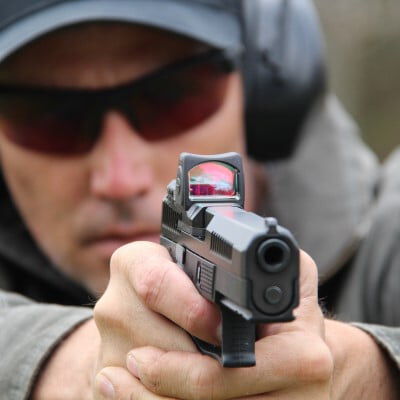shooter looking down a red dot on a pistol