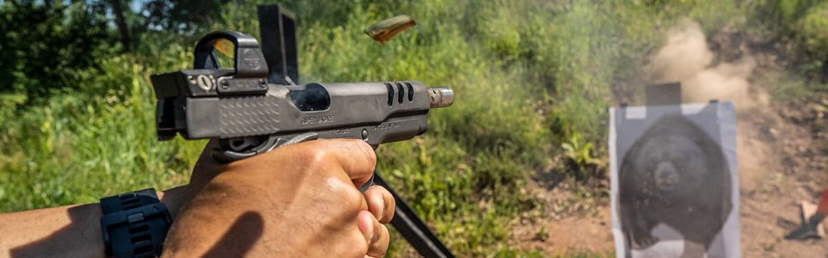 shooter aiming a pistol at a target while outside