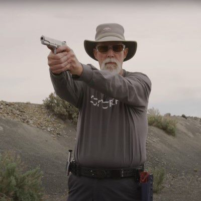 Patrick Kelley aiming a pistol while outside