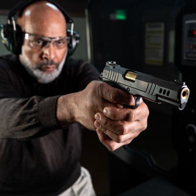 shooter in an indoor range aiming handgun