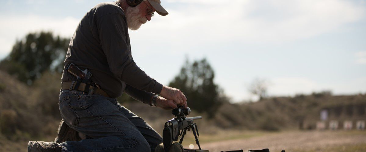 man getting rifle scope ready at an outdoor range