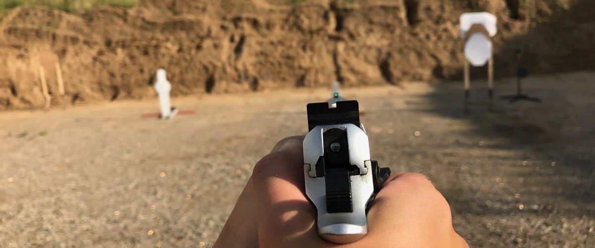 A handgun being pointed at an outdoor target
