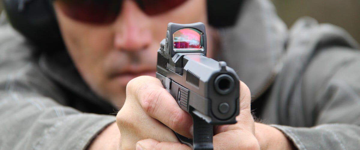 shooter looking down a red dot on a pistol