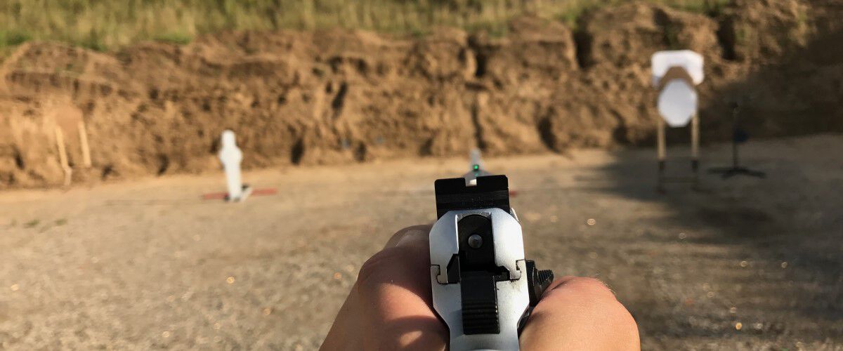 pistol being aimed at a couple targets at an outdoor range
