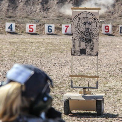 shooters aiming at a bear target at an outdoor range