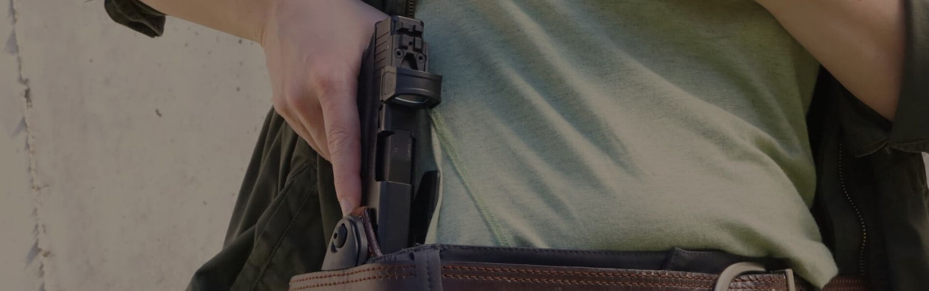 person removing a handgun from a gun holster hiding behind belt loop