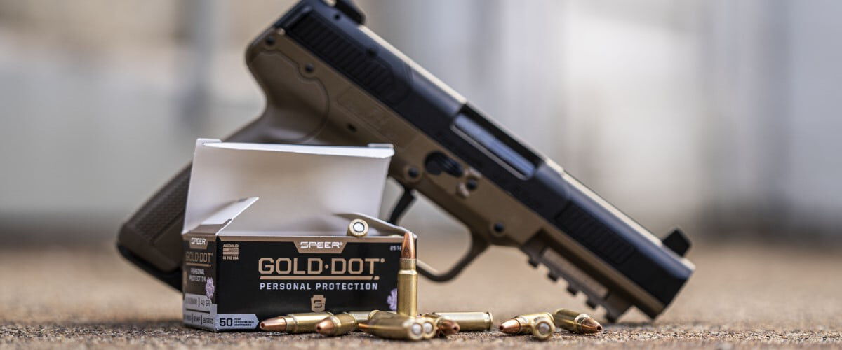 Gold Dot Personal Protection box and cartridges sitting on the ground with a handgun in the background