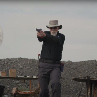 Patrick Kelley aiming a pistol while outside