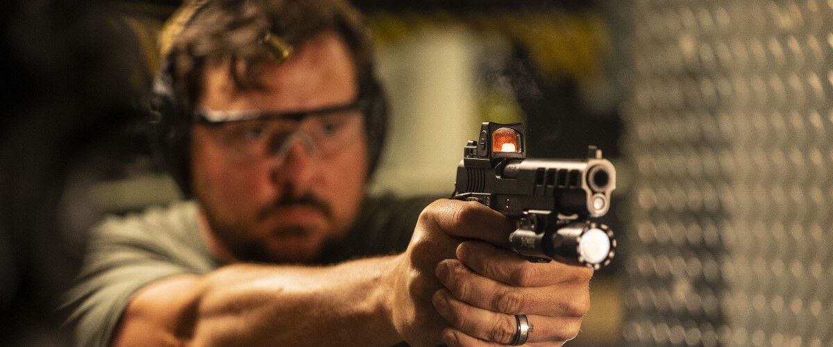 Person pointing a handgun in an indoor range