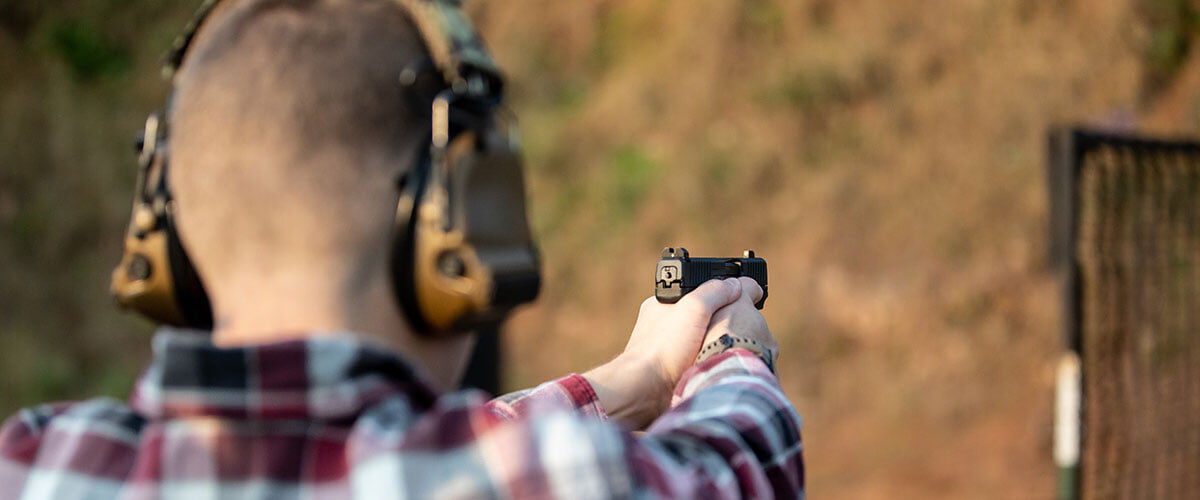 shooter aiming handgun at target oustide