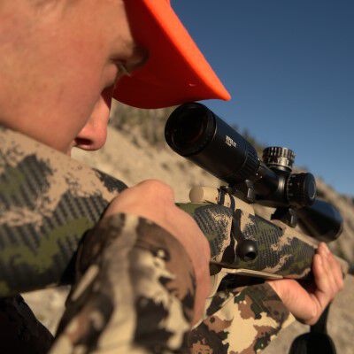 hunter looking down a rifle scope outside