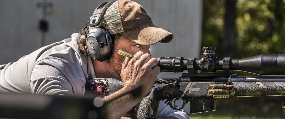 Jim Gilliland looking through a rifle scope while in a prone position