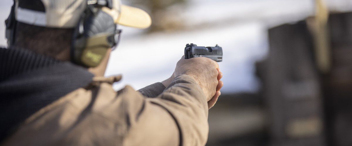 man pointing handgun outside