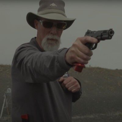 Patrick Kelley aiming a pistol while outside