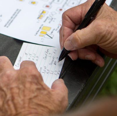 man writing down data on a notecard