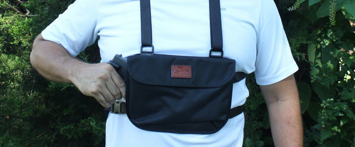 person removing a handgun from a bag on their chest