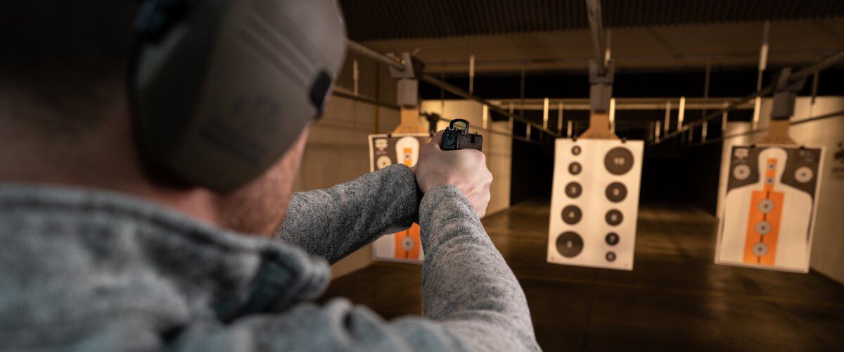 shooter aiming a handgun at a target in an indoor range